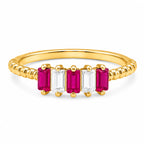 Gold ring with red and clear gemstones on a white background
