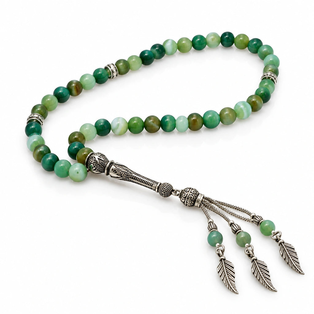 Banded Green Agate tasbih with mint, olive and deep green beads and a silver-tone three-chain leaf tassel on white.