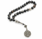 Black Agate tasbih with grey and cream markings, silver-tone imame and circular knot ornament on white.
