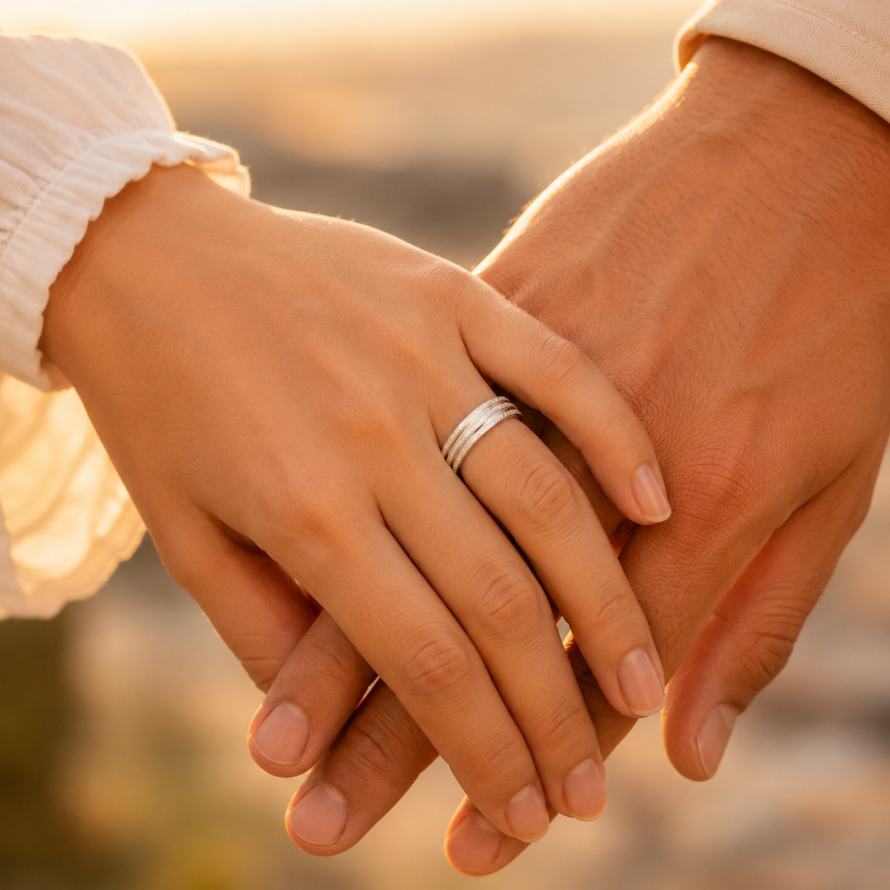 Close-up of two hands holding each other with a warm, blurred background