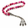 Pink Agate tasbih with banded rose beads, silver-tone imame and three tulip-shaped tassel charms on white.