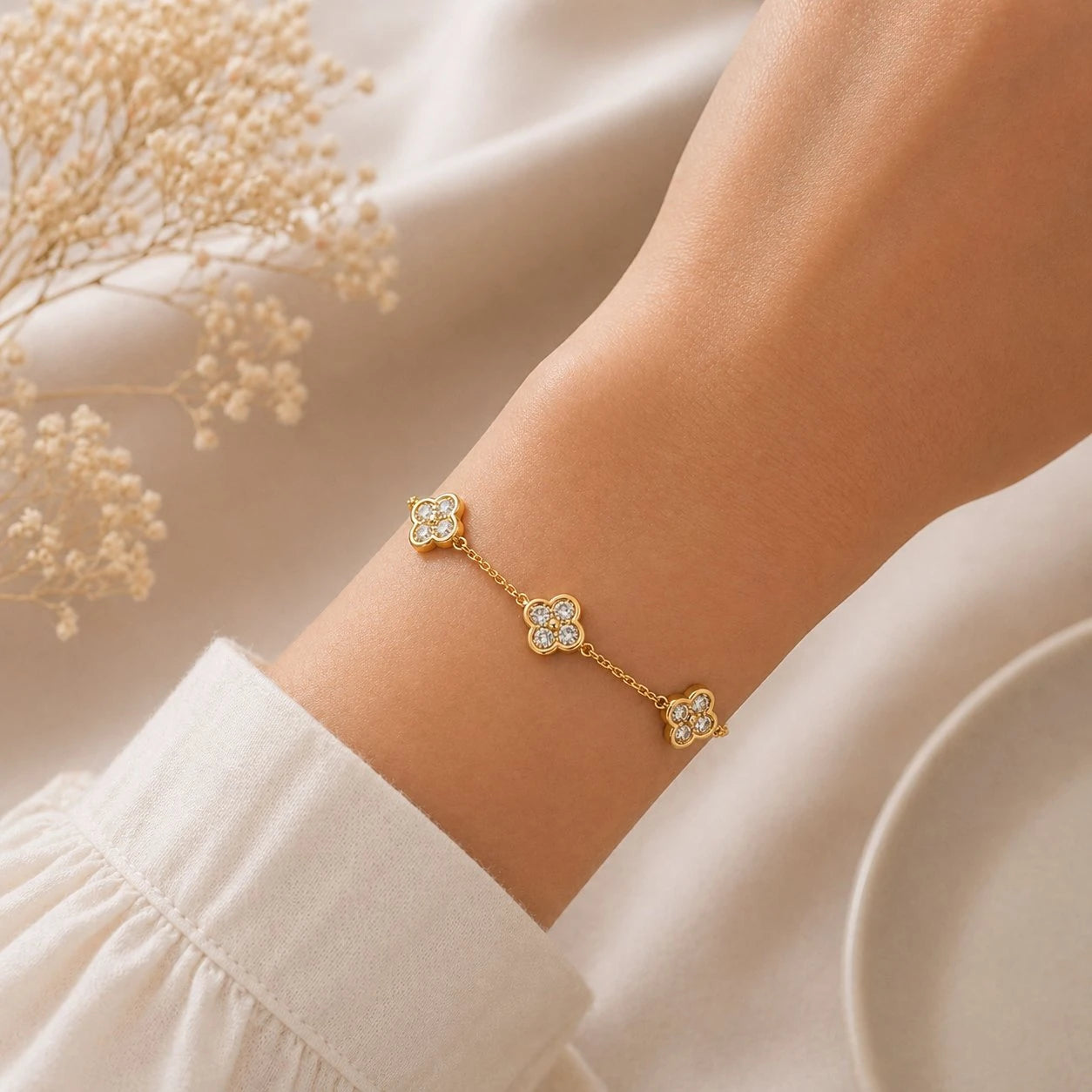 Gold bracelet with floral designs on a wrist against a neutral background