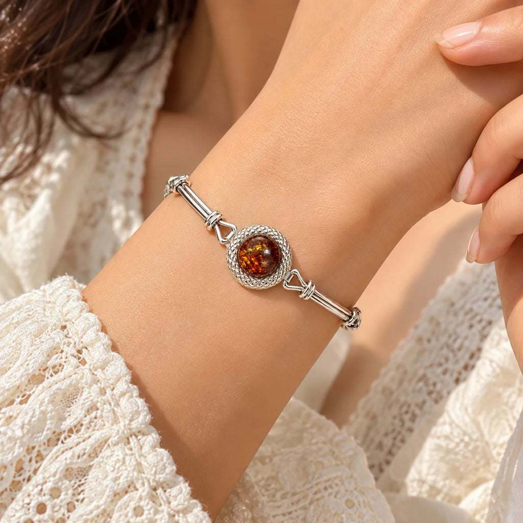 Women's 925 sterling silver amber bracelet worn on woman's wrist, close-up lifestyle shot with white lace sleeve, Fine Silver KSA