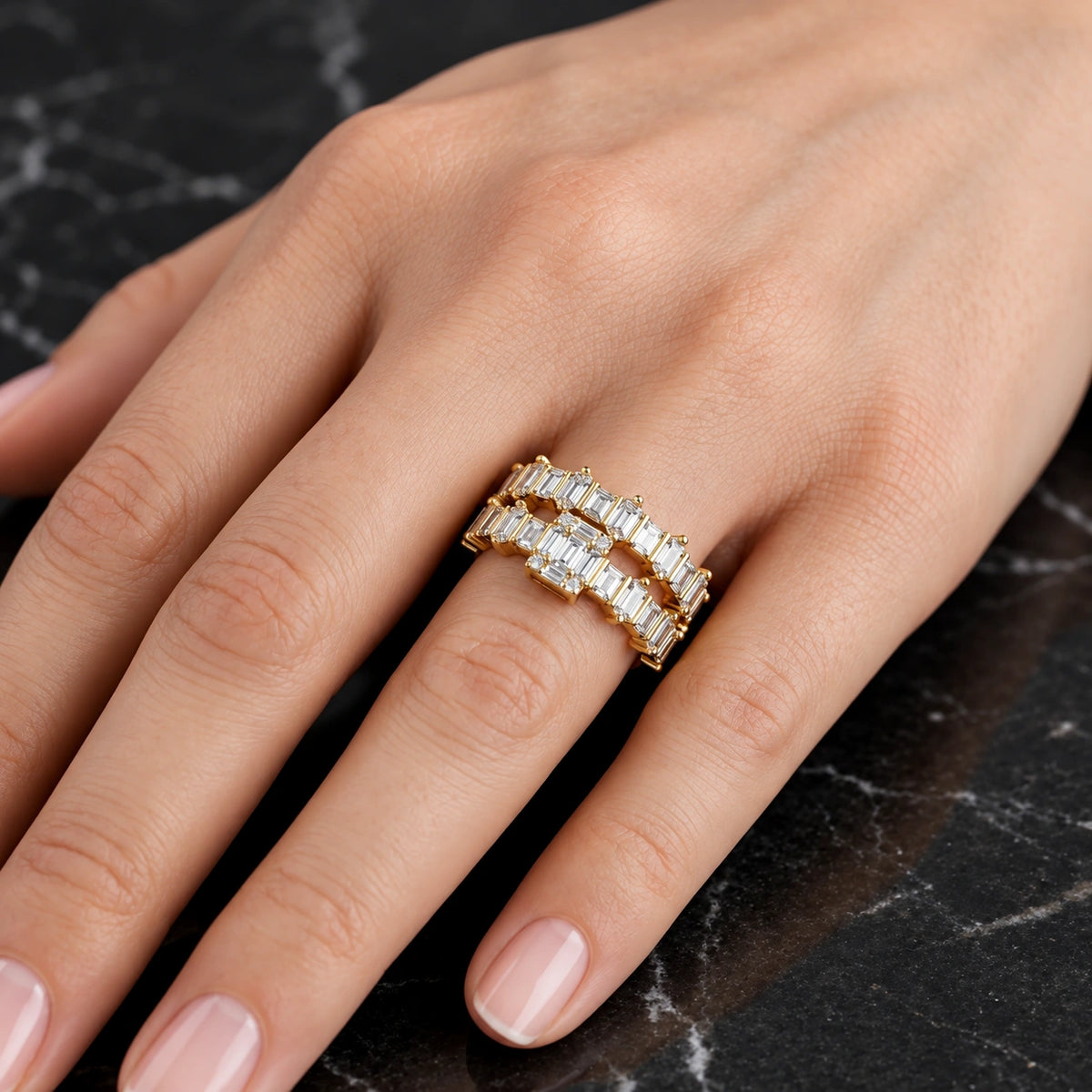 Women's gold-plated 925 silver baguette CZ eternity band ring worn on woman's finger against marble background, Fine Silver KSA
