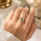 Gold ring with a green gemstone on a hand against a blurred background