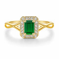 Gold ring with a green gemstone and diamond accents on a white background