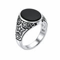 Silver ring with black stone and star design on a white background