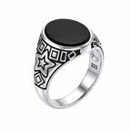 Silver ring with black stone and star design on a white background