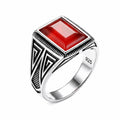 Silver ring with a red stone on a white background
