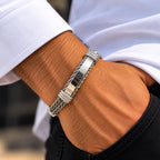Men's silver cable cuff bracelet with a polished centre bar worn on a wrist beside a white cuff.