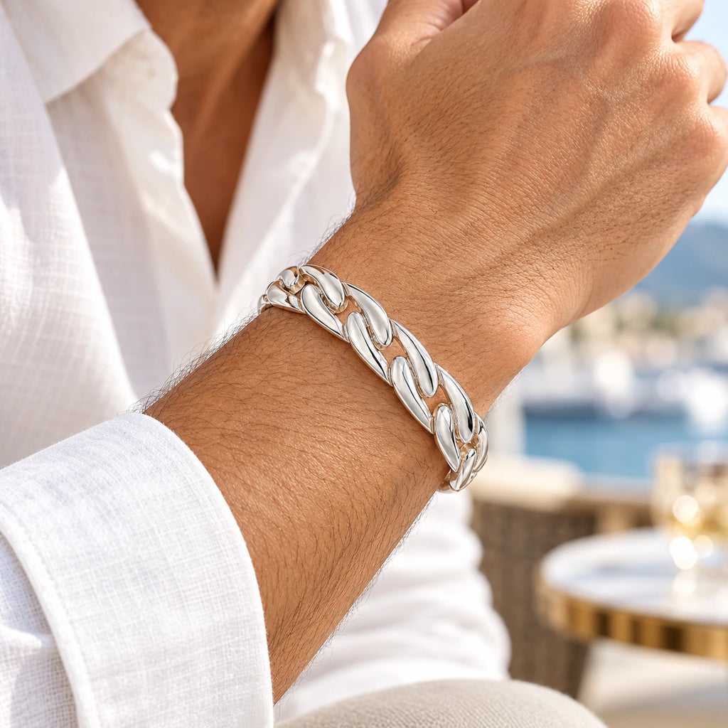 Men's polished silver chain-link cuff bracelet worn on a wrist beside a white shirt cuff.