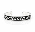 A silver-toned open cuff bracelet featuring a black enamel inlay with a raised braided chain pattern, photographed on a clean white background with a soft reflection.