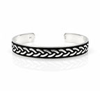 A silver-toned open cuff bracelet featuring a black enamel inlay with a raised braided chain pattern, photographed on a clean white background with a soft reflection.