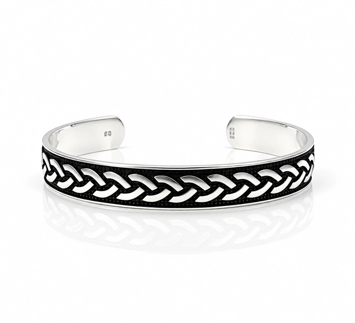 A silver-toned open cuff bracelet featuring a black enamel inlay with a raised braided chain pattern, photographed on a clean white background with a soft reflection.