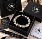 Silver crescent-link bracelet displayed in a black presentation box with branded bag, card, ribbon and cloth.