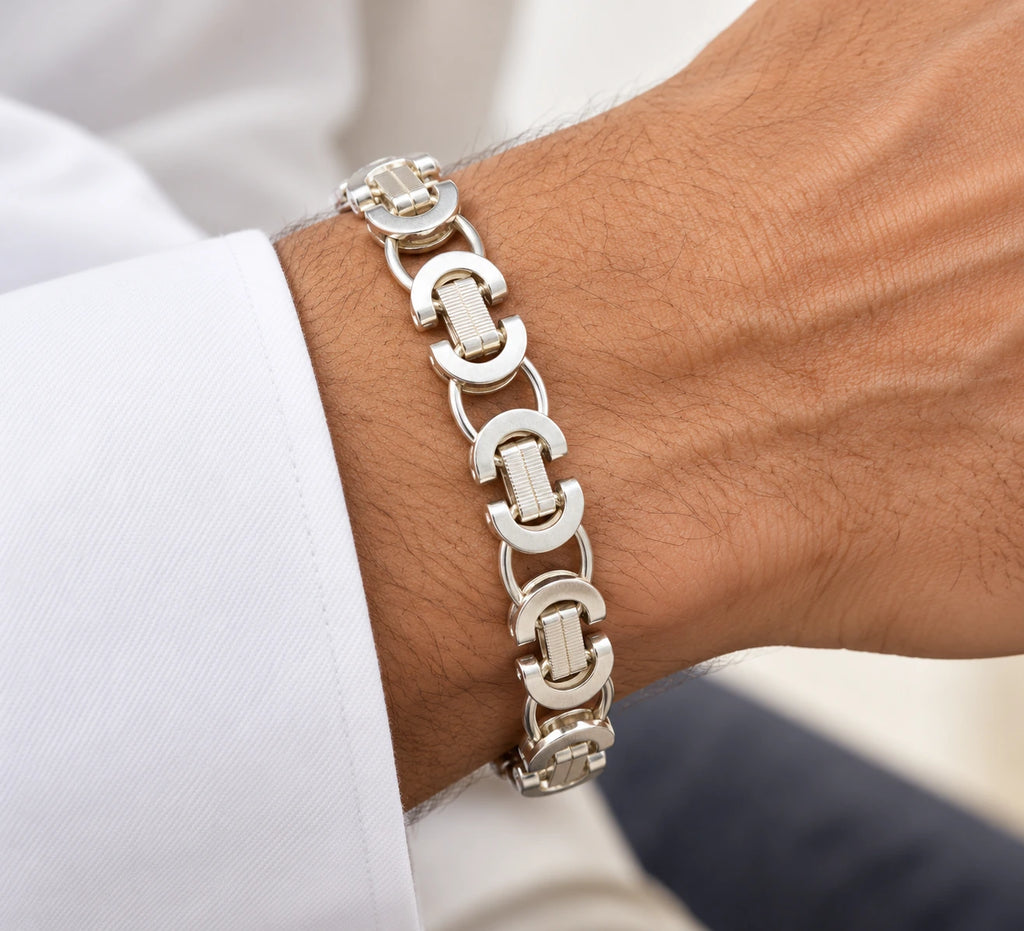 Men's silver crescent-link bracelet with ridged connecting bars worn on a wrist beside a white cuff.