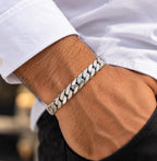 Men's polished silver Cuban-link bracelet worn on a wrist beside a white shirt cuff.