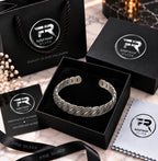 Engraved silver cuff bracelet in a black presentation box with branded bag, authenticity card, ribbon and cloth.