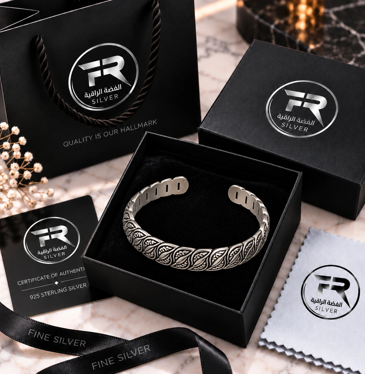 Engraved silver cuff bracelet in a black presentation box with branded bag, authenticity card, ribbon and cloth.