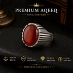 Silver ring with a red stone on a dark background, featuring Premium Aqeeq branding.