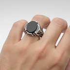 Silver ring with black stone on a light gray background