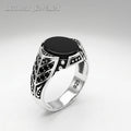 Silver ring with black stone on a light gray background