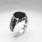 Silver ring with black stone on a light gray background
