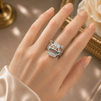 Hand wearing a decorative ring with gemstones on a neutral background
