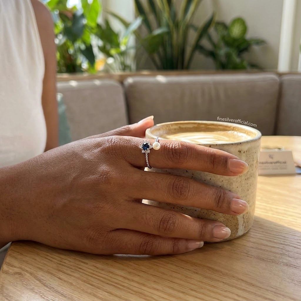 Women's 925 silver blue sapphire CZ pearl open ring worn on finger, lifestyle shot at café, finesilverofficial.com