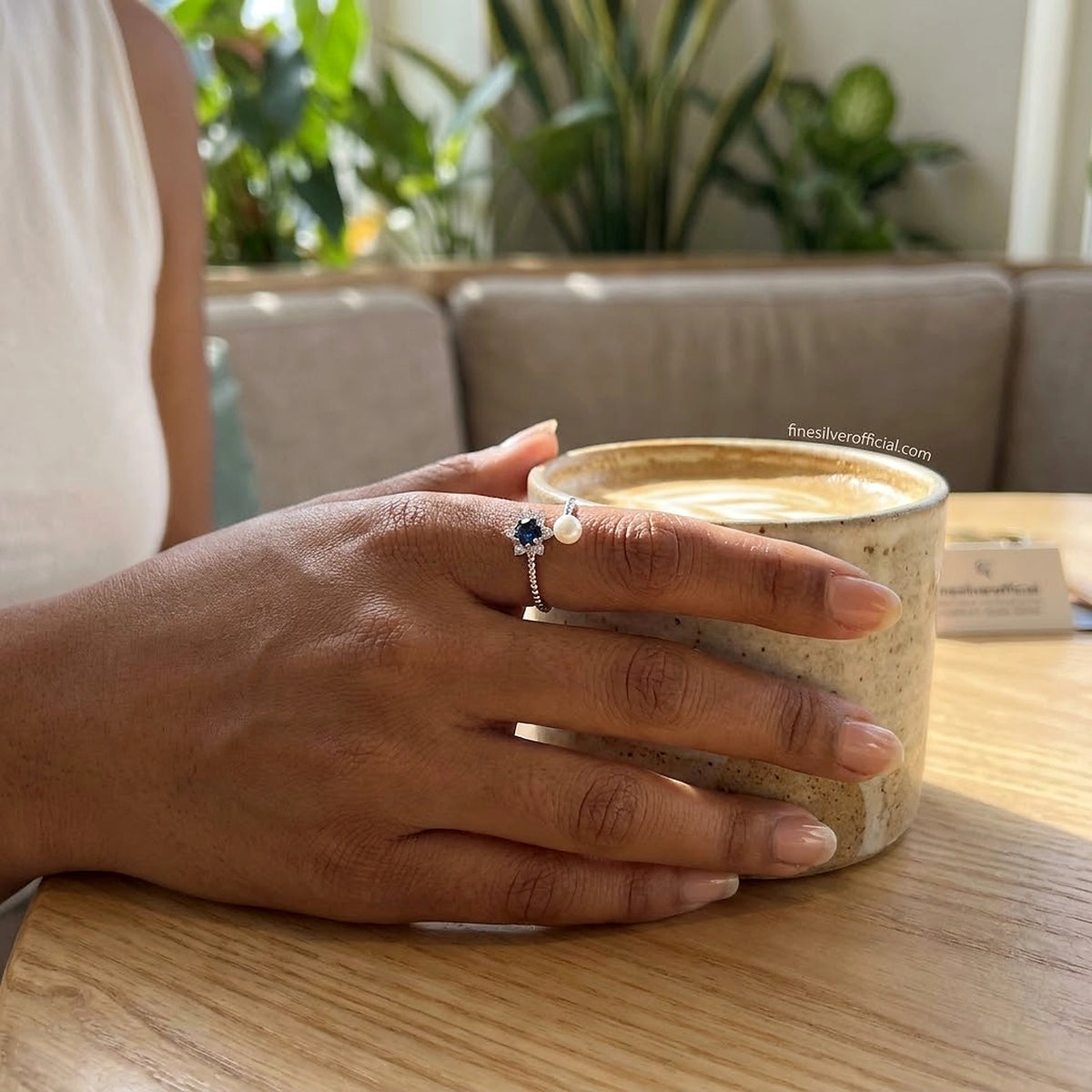 Women's 925 silver blue sapphire CZ pearl open ring worn on finger, lifestyle shot at café, finesilverofficial.com